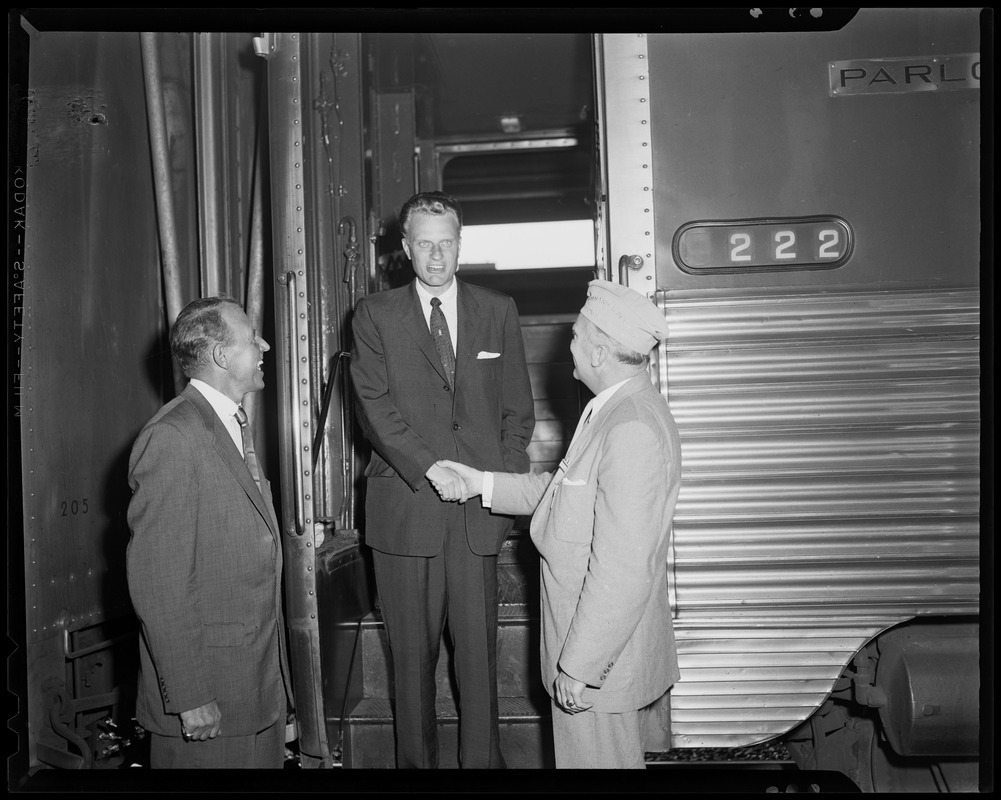 Billy Graham shakes hands with VFW National Commander Merton B. Tice (right), as city greeter Jack Brown looks on (left)