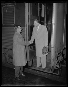 Billy Graham on stairs of train, shaking hands with other man