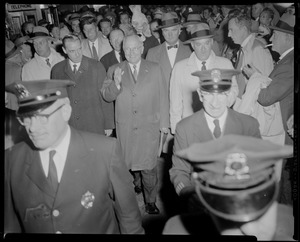 Edward McCormack, Harry Truman, John F. Kennedy, and large crowd walking, with police officers leading