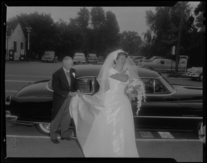 Jerrine Soper with Cadillac behind her and man tending to train of her wedding gown