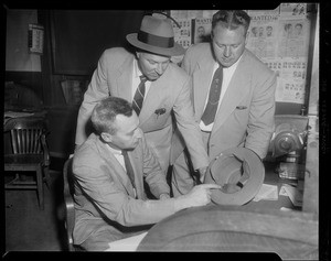 Three men examining a hat, most likely related to Elmer "Trigger" Burke case