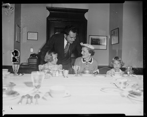 Vice President Richard Nixon leaning over as his wife Pat and daughters Patricia and Julie eat lunch at the table