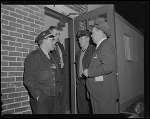 Four men standing outside of a doorway