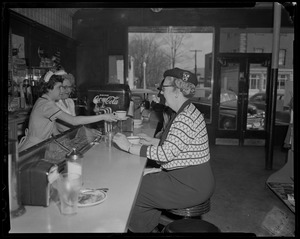Waitstaff serving drinks to customers seated at counter in diner