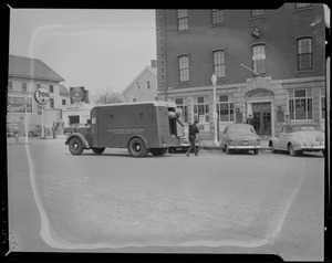 Two men exiting armored truck parked outside building