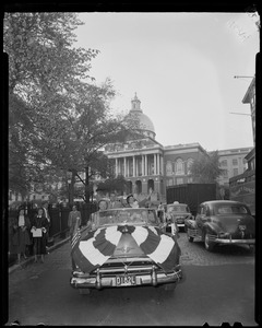 Richard and Pat Nixon waving from open car with Massachusetts State House in background