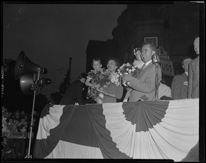 Richard and Pat Nixon holding girls with bouquets at rally