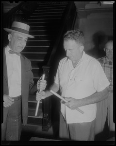 Two men examining bars or pipes