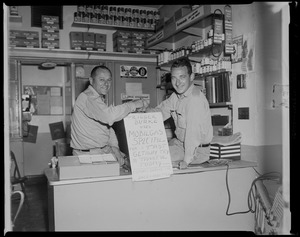 Two men with sign at Edmor's Service Station that reads "Trigger Burke uses Mobilgas Special for a fast getaway try a tankful today"