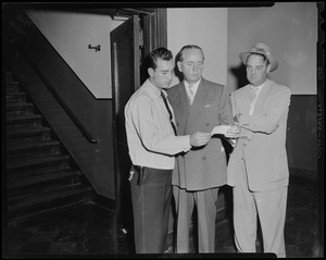 Patrolman Edward A. Giampaolo, Assistant District Attorney Edward M. Sullivan, and Detective Daniel Crowley examining photograph, likely of Anthony Pino