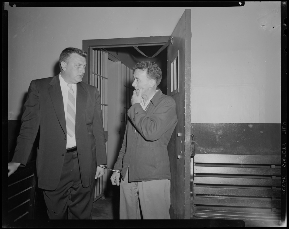 Elmer Burke and other man talking next to open door, handcuffed to each other