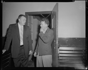 Elmer Burke and other man talking next to open door, handcuffed to each other