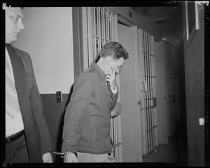 Elmer Burke turning toward cells and handcuffed to other man