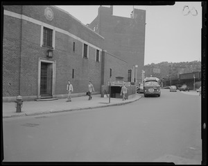 Street scene with pedestrians and vehicles near underpass entrance, outside Charles Street Jail