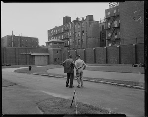 Two men standing on grounds of Charles Street Jail with view of walls and guard tower