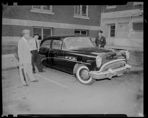 Two uniformed police officers and man holding rifle standing next to car