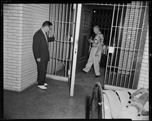 Men looking at jail cell door with two bars missing