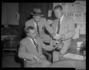 Three men looking at hat with wanted posters behind them