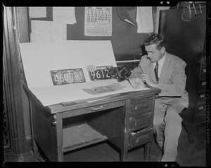 Man at desk with license plates