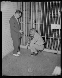 Men examining two bars taken from jail cell door