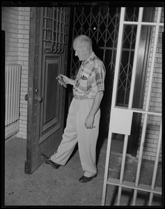 Man with tool examining door