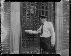 Boston police officer pointing at gated security door at Charles Street Jail