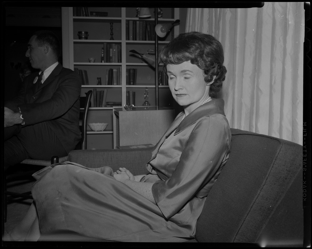 Mrs. Margaret M. Heckler seated, with husband John in background