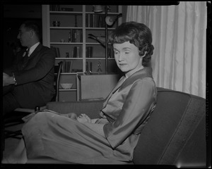 Mrs. Margaret M. Heckler seated, with husband John in background