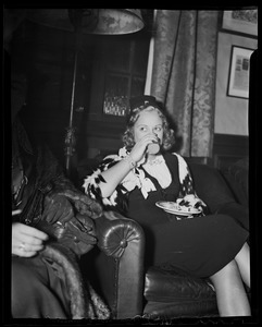 Sonja Henie, seated, drinking from cup