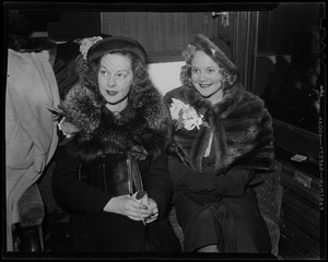 Sonja Henie seated with other woman, both wearing furs