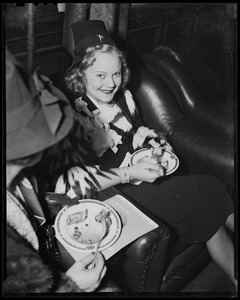Sonja Henie seated with another woman, holding plate