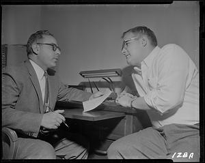 Two men talking across a desk