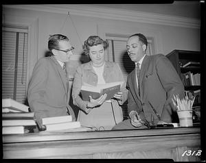 Three people looking at a book