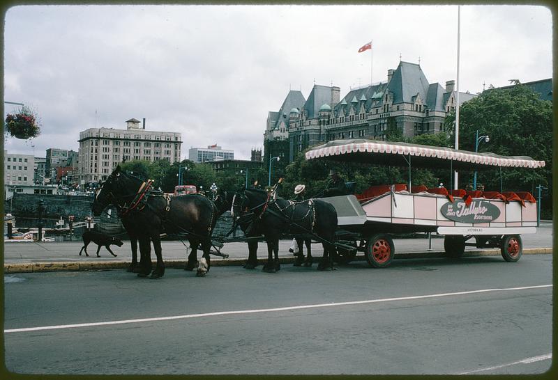 Horse-drawn sightseeing vehicle on street next to The Empress Hotel, Victoria, British Columbia