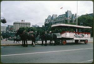 Horse-drawn sightseeing vehicle on street next to The Empress Hotel, Victoria, British Columbia