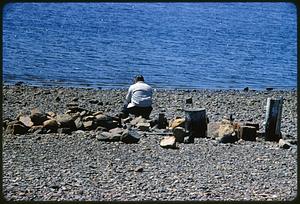 Man sitting on rocky beach, Boston