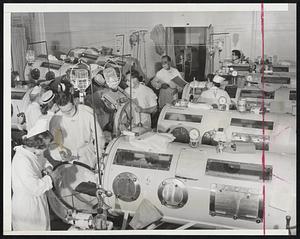 Emergency Polio Ward- A general view yesterday in a corner of the emergency polio ward at Haynes Memorial Hospital. Teams of doctors and nurses are giving emergency treatment to critical bulbar cases. There are 21 iron lungs in this room supplied by the National Foundation for Infantile Paralyses, which has brought 61 of the respirators into the city. The critical patients are lined up close together so hard-pressed medical teams can give them fast emergency treatment.