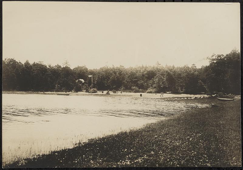 Beach on the lake - with a flag, firepit, cabin, and a boat on the right