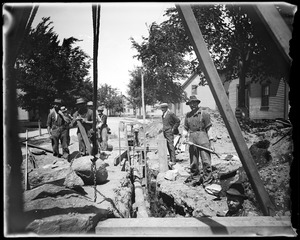 Sewer construction, showing the raising of town water pipe for sewer to pass under