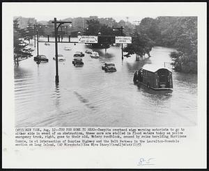 Too Far Gone to Read -- Despite overhead sign warning motorists to go to either side in event of an obstruction, these cars are stalled in flood waters today as police emergency truck, right, goes to their aid. Watery roadblock, caused by rains heralding Hurricane Connie, is at intersection of Sunshine Highway and the Belt Parkway in the Laurelton-Rosedale section on Long Island.