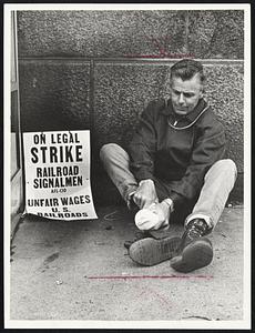 George Kelly of the railroad signalmen's union, which struck the nation's railroads yesterday, massages his feet outside South Station where he is on picket duty.