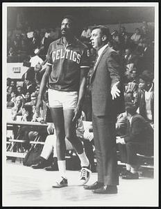 Bill Russell listens to an unidentified man by the basketball court