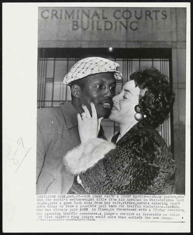 New Champ Faces a Court Battle-- Johnny Saxton, who won the world's welterweight title from Kid Gavilan in Philadelphia last night, gets a good luck kiss from his wife, Vivian, before entering court here today to face a possible jail term for traffic violations. Saxton, who has already paid $650 in fines, is threatened with a 15-day sentence for ignoring traffic summonses. A judge's verdict as favorable as those of last night's ring judges would more than satisfy the new champ.