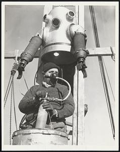 Cyril Von Baumann, writer and explorer, is shown March 22 as he gave a new type diving suit a successful tryout at Toms River, N.J. The cylinder Von Baumann holds supplies the diver with a mixture of helium and oxygen and eliminates necessity of the usual air line. The suit will withstand pressure of 1200 pounds per square inch and is expected to make possible dives to a depth of 2000 feet for periods as long as 12 hours.