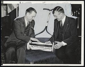The Last Lawnmower to be produced by a Massachusetts company which has diverted to strictly defense products was presented Gov. Saltonstall at the New England Hardware Dealers' Association meeting today. The Governor is shown, at right, with President John T. Skolfield at the Hardware Dealers examining the mower, which is made chiefly of aluminum, a valuable defense material.
