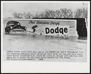 Deceiving Isn't it?-- Water from the flooding Missouri River produced this today as the car on a signboard along inundated U.S. route 20 looks as though it's driving atop water and a skier on the sign seems headed for the drink.