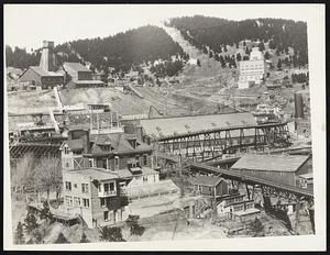 "Thar's Gold in Them Thar Hills." General view of the famous homestake gold mine at lead, South Dakota, in the Black Hills Region, which produces about $6,000,000 in gold annually. At the upper left is shown one of the older shaft buildings. The white structure at the upper right is a combination shaft building and crusher plant. In the center are shown the buildings in connection with one of the Large Mills. The mine has been in continuous operation since 1876, the year following the discovery of the gold-bearing ore, and in that time has produced over $200,000,000 in gold.