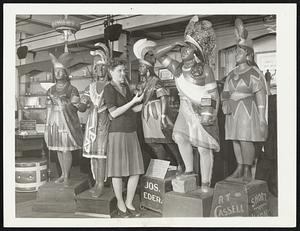 A Reminder of Other Days. If you wonder what has become of all the wooden Indians that once stood in front of cigar stores, you will find many of them in the collection being accumulated in his laboratory on Wabash avenue here by Allen Scott Boyer. In the old days, around the turn of the century, when the figures were plentiful, it took an expert woodcarver about a week to produce one. The price ranged from $100 upward. Now, as Amaricana they are worth they say, their weight in gold. Miss Celia Silska of the Boyer Laboratory is shown with some of Mr. Boyer's collection.