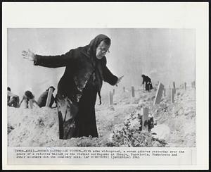 Mourns Earthquake Victim -- With arms widespread, a woman grieves yesterday over the grave of a relative killed in the violent earthquake at Skopje, Yugoslavia. Tombstones and other mourners dot the cemetery site.