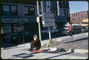 A street vendor sitting by a parking lot, Boylston Street,